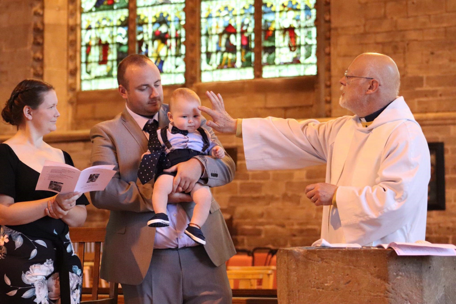 Family with baby to be baptised being blessed by the Rector